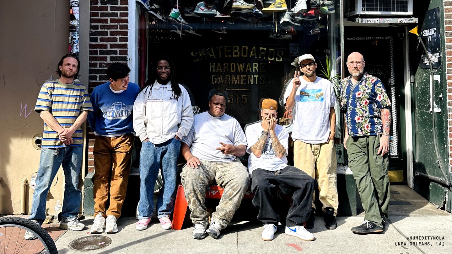 Photo of a group of people sitting outside of a skate shop.