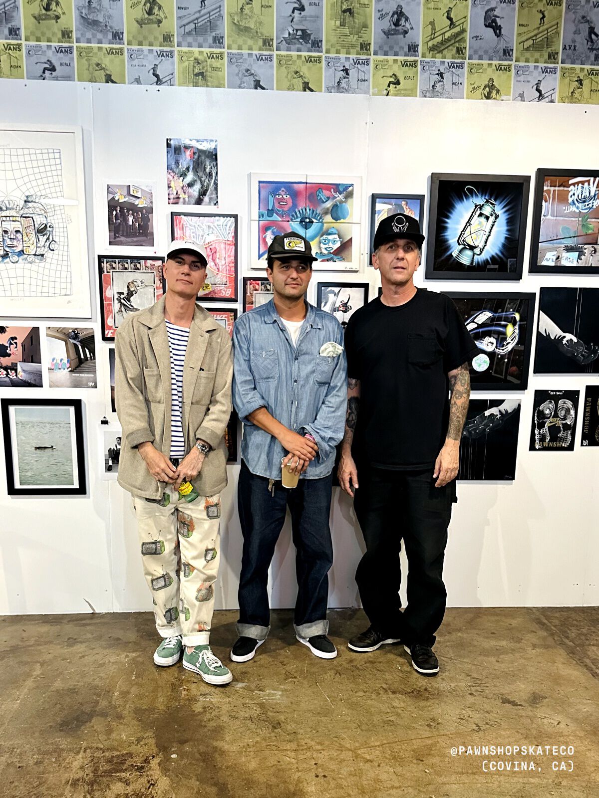 Photo of three people standing in front of a gallery wall.